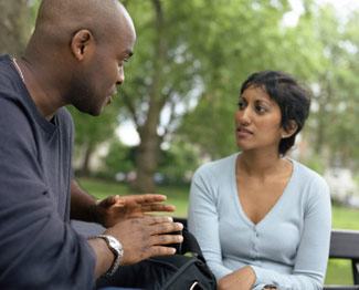 A man talking to a woman on a park bench